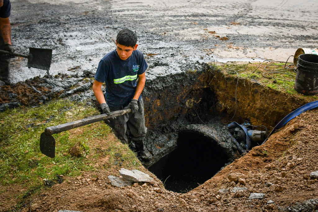 Trabajador municipal realizando zanjeo y desobstrucción de drenaje con herramientas de mano