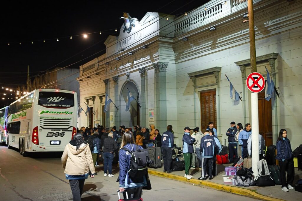 Delegación de 295 integrantes de San Vicente con bolsos y valijas frente a la fachada del Palacio Municipal antes de salir a Mar del Plata