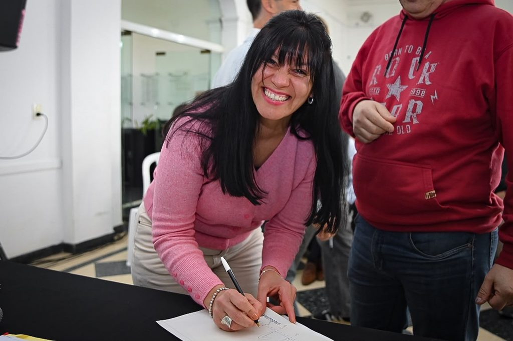 Firma de escrituras | Un verdadero golazo para 185 familias del barrio Papa Francisco 4 Vecinos del Barrio Papa Francisco sonrientes firmando la documentación dominial de sus lotes en San Vicente.