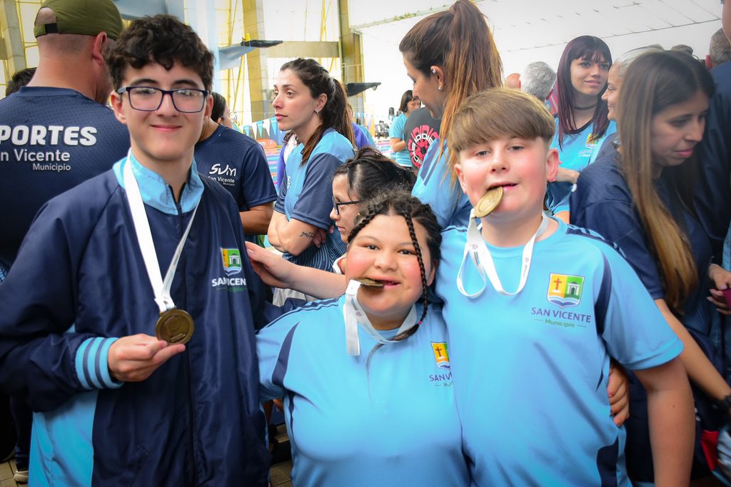 COSECHA HISTÓRICA | La brillante actuación de los atletas PCD de San Vicente quiebra todos los récords en Mar del Plata 4 Chicos y chicas nadadores PCD de San Vicente posando sonrientes mordiendo sus medallas doradas ganadas en los Bonaerenses.